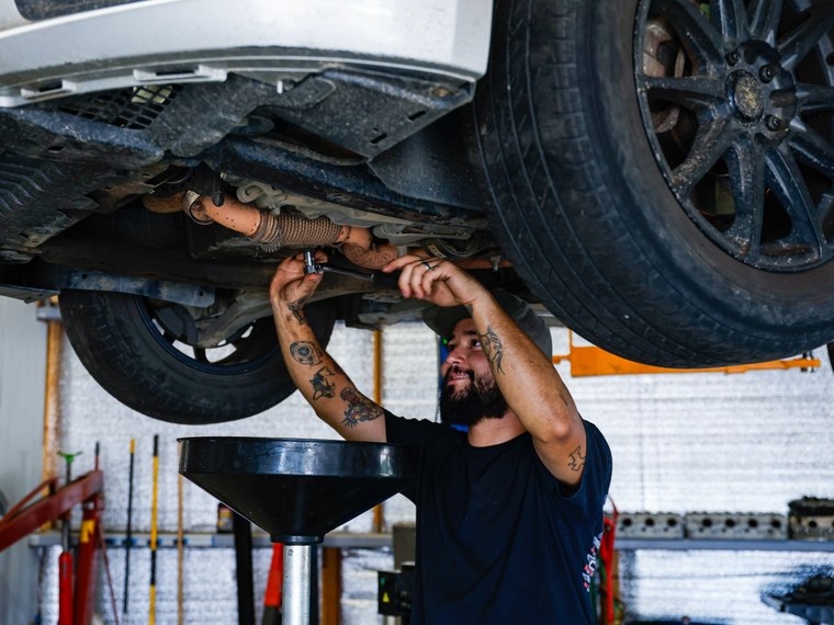 Technician removing the drain plug during an oil change in North Little Rock, Arkansas